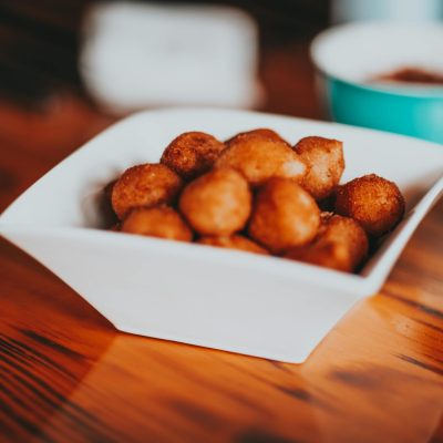 High angle of square ceramic bowl with yummy fried sweet snacks served on wooden table in kitchen